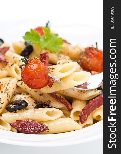 Penne pasta with sausage, cherry tomatoes and olives, close-up, vertical