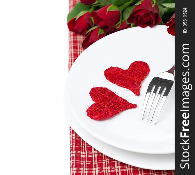 Two wicker heart on a plate and red roses, isolated on white