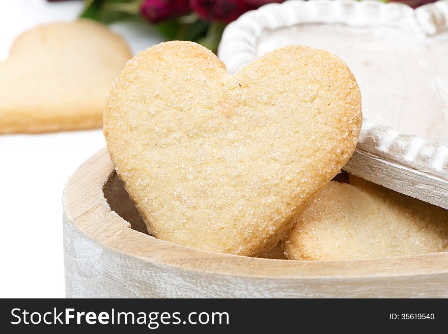Wooden box with cookies in the form of heart, close-up, on white