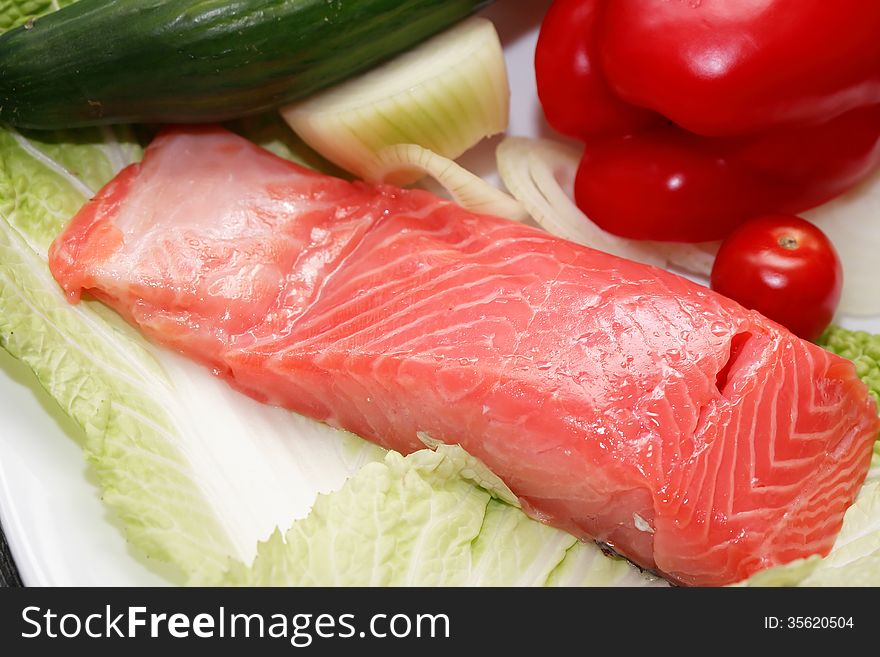 Closeup of filleted trout on plate near various vegetables. Closeup of filleted trout on plate near various vegetables