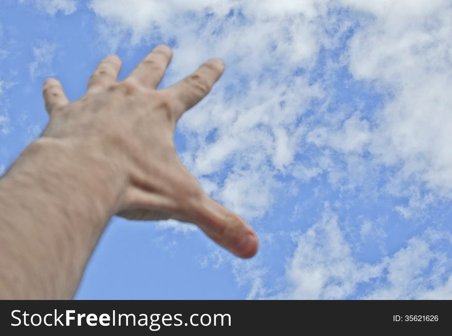 Hand stretched to the blue cloudy sky. Hand stretched to the blue cloudy sky