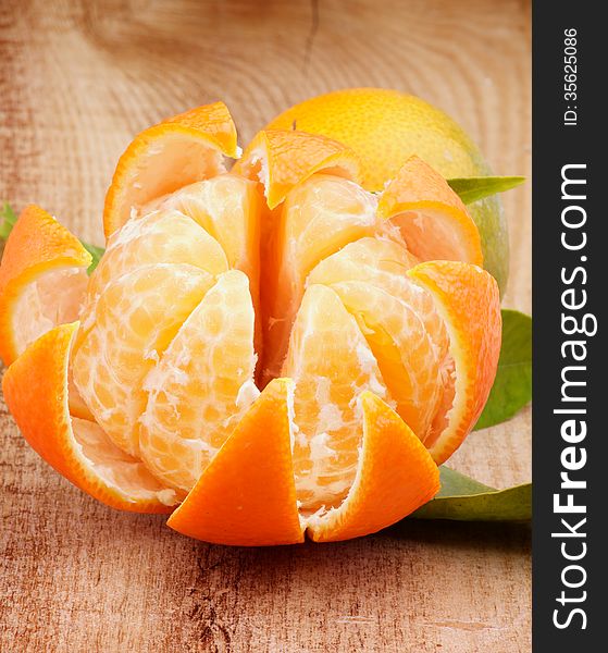 Fresh Ripe Tangerine with Segments and Citrus Peel closeup on Wooden background