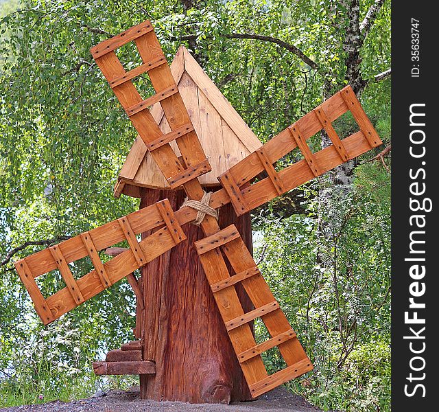 Wooden windmill on the background of birch