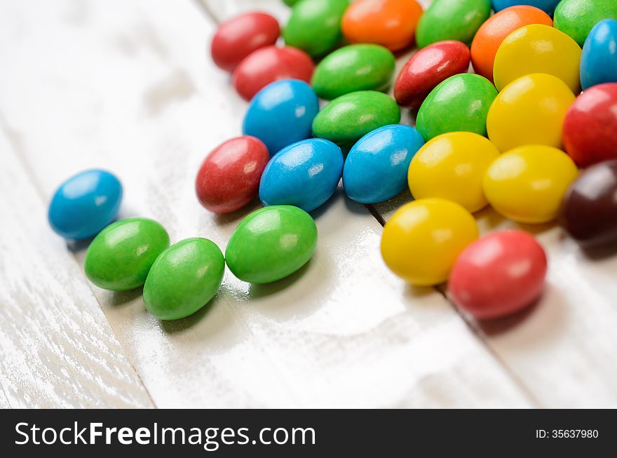 Colorful candy balls on white wooden plank table. Macro shot