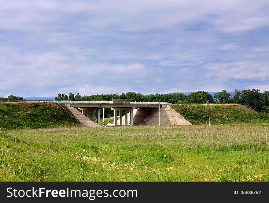 Bridge over a highway against a summer landscape with a meadow. Bridge over a highway against a summer landscape with a meadow