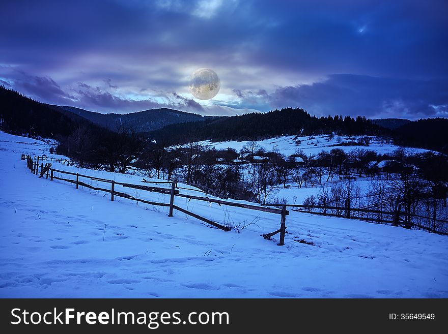 Fence by the road to snowy forest in the mountains