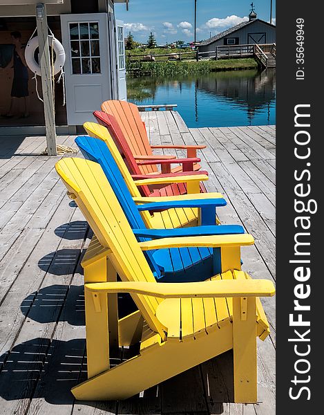 Wooden chairs of different colors on a wooden deck near the lake. Wooden chairs of different colors on a wooden deck near the lake