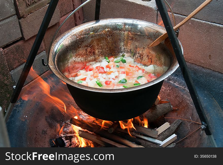 Hungarian goulash cooked in a copper pot over a fire in the backyard