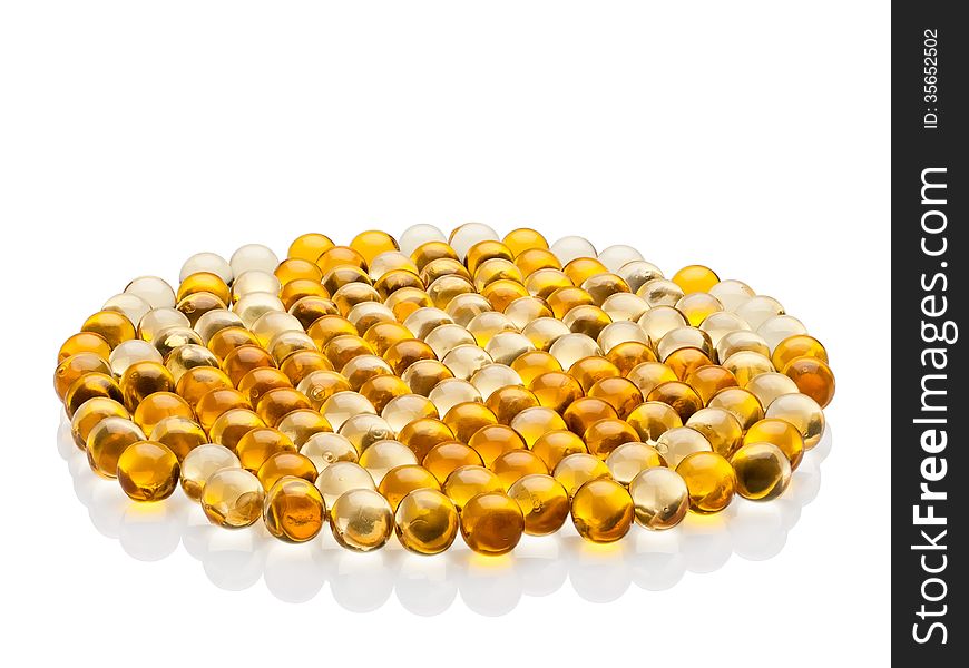 Many transparent, yellow pills with cod-liver oil on white background