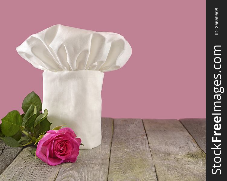 White chef's toque with pink rose isolated on pink. White chef's toque with pink rose isolated on pink