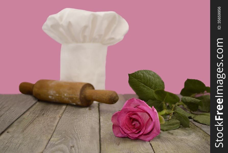 Chef's toque with pink rose and rolling pin on pink. Chef's toque with pink rose and rolling pin on pink