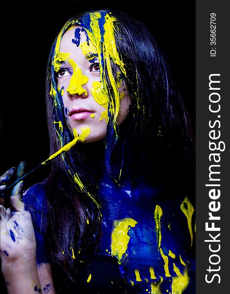 Beauty/fashion Close Up Portrait Of Woman Painted Blue And Yellow With Brushes And Paint  On Black Background