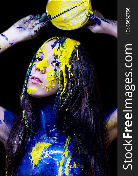 Beauty/fashion Close Up Portrait Of Woman Painted Blue And Yellow With Brushes And Paint  On Black Background