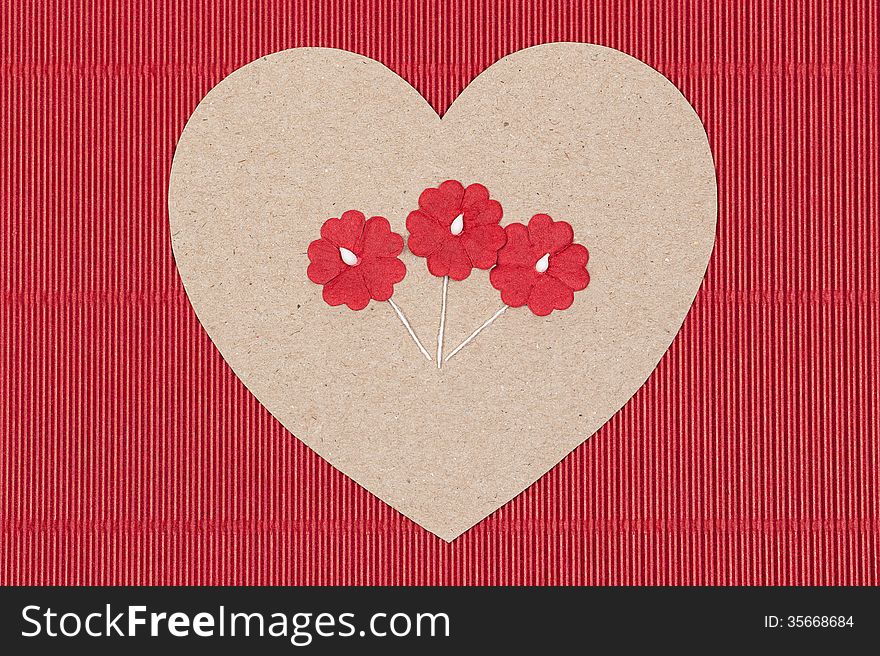 Cardboard heart with paper flowers on red goffer background.