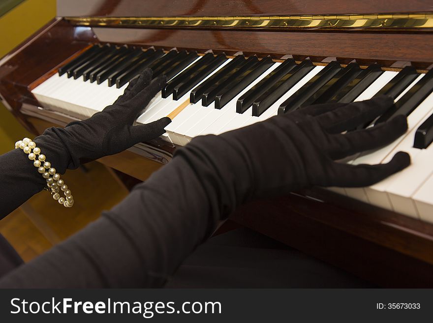 A classy woman in vintage gloves playing piano. A classy woman in vintage gloves playing piano