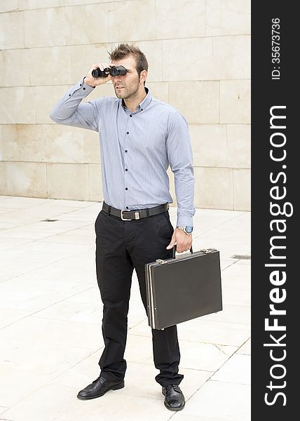 Businessman with briefcase looking through binoculars.