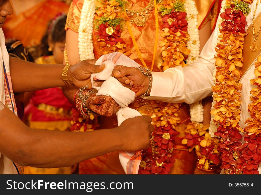 Cropped picture of a wedding couple holding their hands together to tie a knot with a cloth