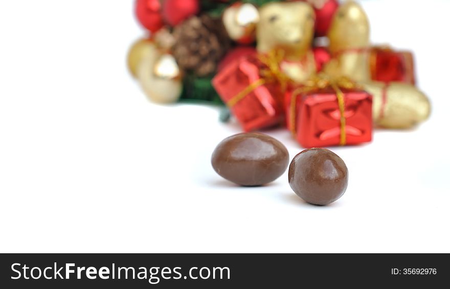 Chocolate eggs in front of Christmas gifts on white background
