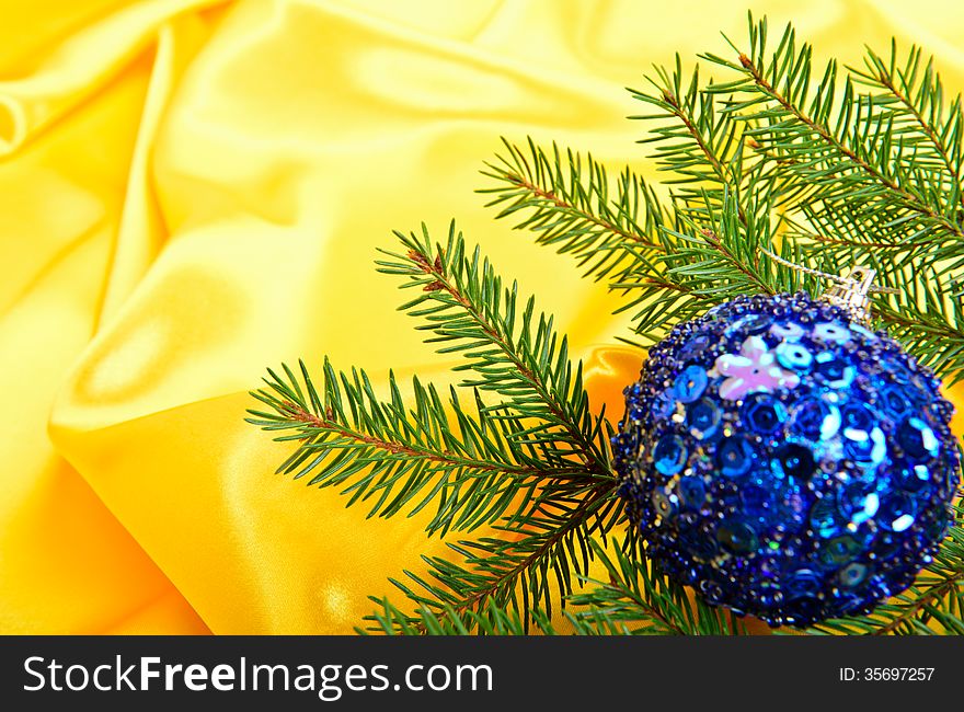 Christmas tree and ball on a gold silk background. Christmas tree and ball on a gold silk background