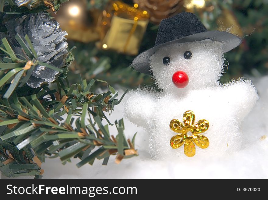 Cute snowman to a dark hat in an environment of snowdrifts and christmas evergreen trees