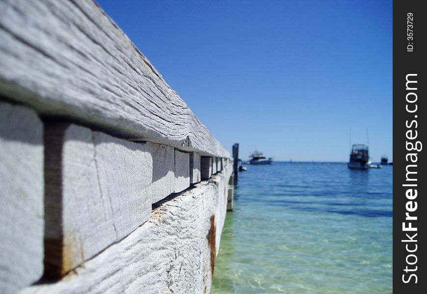 Perspective view of wooden pier jetty with boats in the background, shallow depth of field