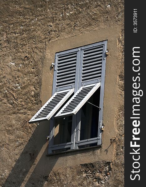 Window in the old rugged house with the gray shutters. Window in the old rugged house with the gray shutters