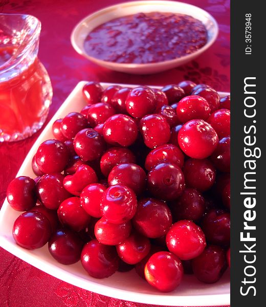 Fresh cherry in bowl, raspberry cooking and beverage on table