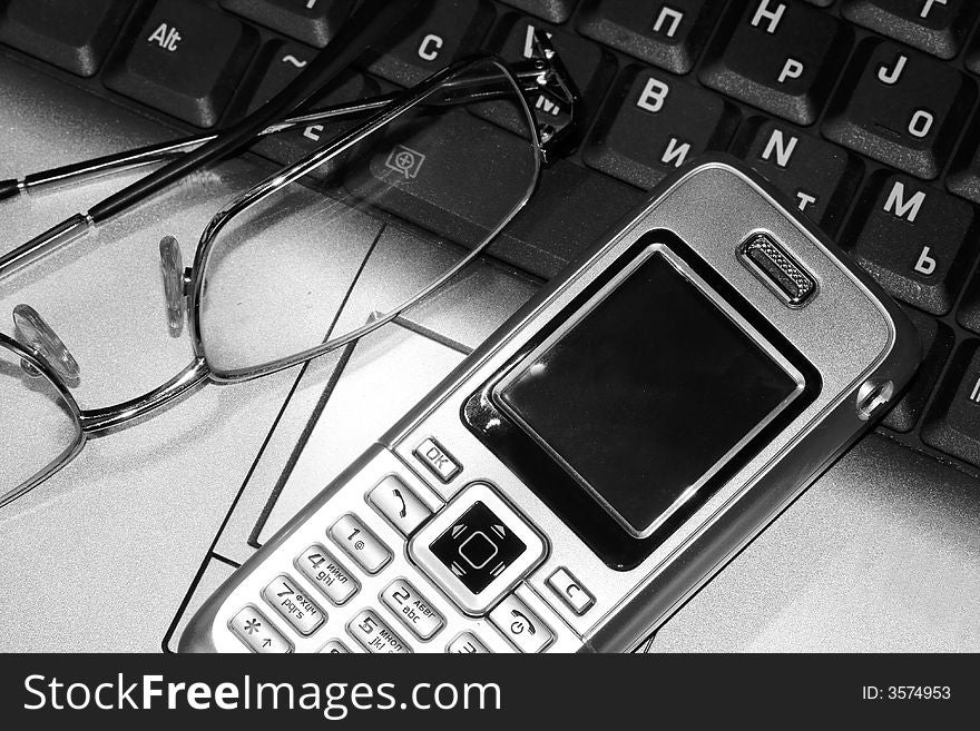 Mobile phone and glasses on computer keyboard (business conception)