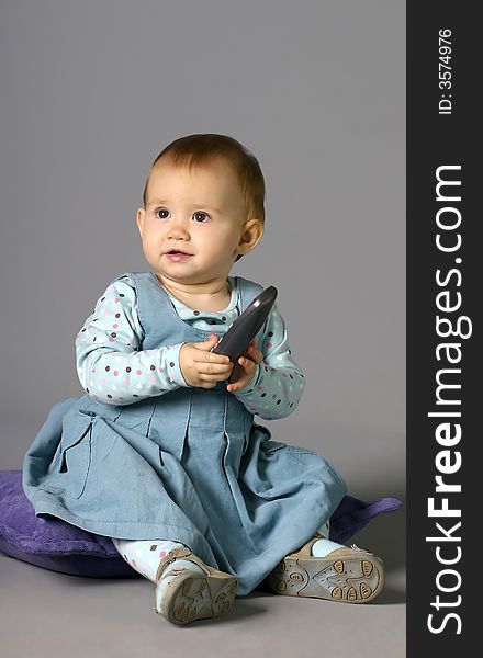 The child calling by phone on a grey background with a smile