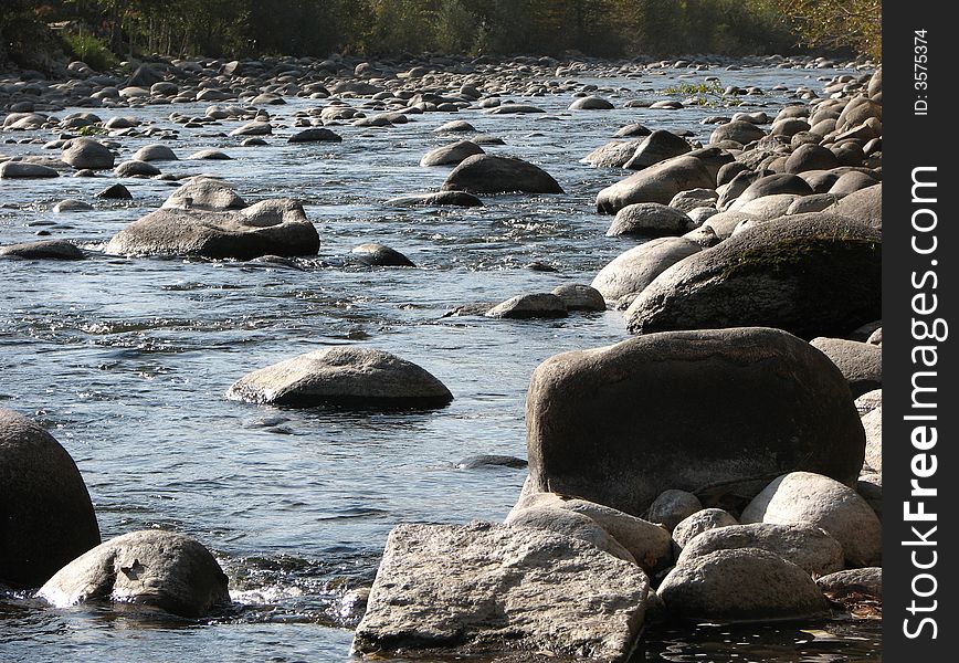 A river with a lot of round stones under sunshine. A river with a lot of round stones under sunshine