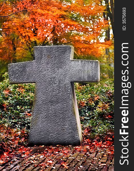 Cross monument on a cemetery in autumn