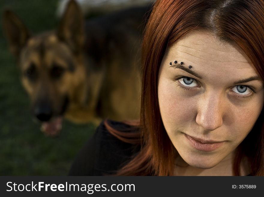 A girl seductively staring at the camera with her dog (german shepherd) in the background. A girl seductively staring at the camera with her dog (german shepherd) in the background.