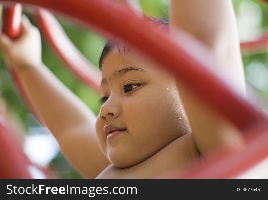 Close up photo of kid playing inside red bars playground. Close up photo of kid playing inside red bars playground