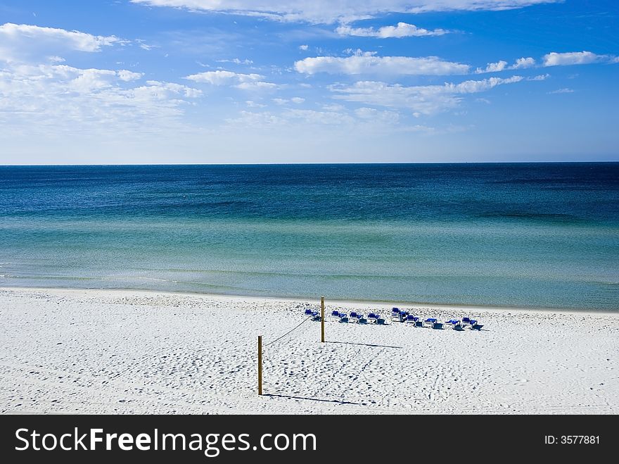 Picture of a volleyball net and benches on a beach facing the sea signifying fun and relaxation. Picture of a volleyball net and benches on a beach facing the sea signifying fun and relaxation