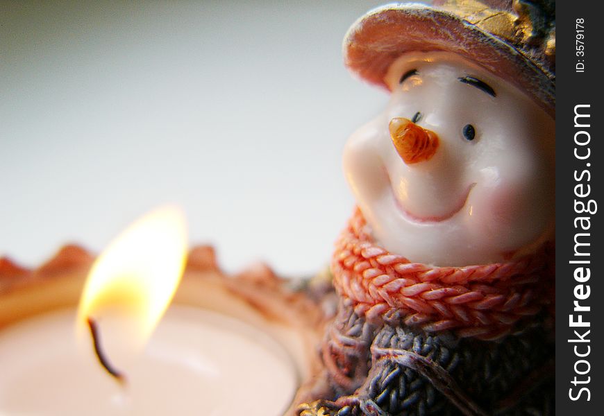 Little snowman and burning tea-candle. Little snowman and burning tea-candle