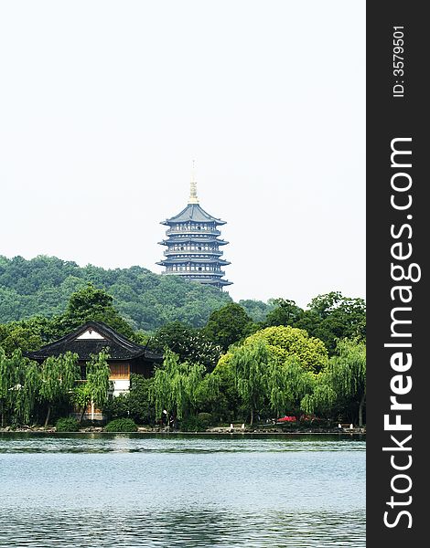 Asian tower near a lake with Asian house and green willow trees. Asian tower near a lake with Asian house and green willow trees.