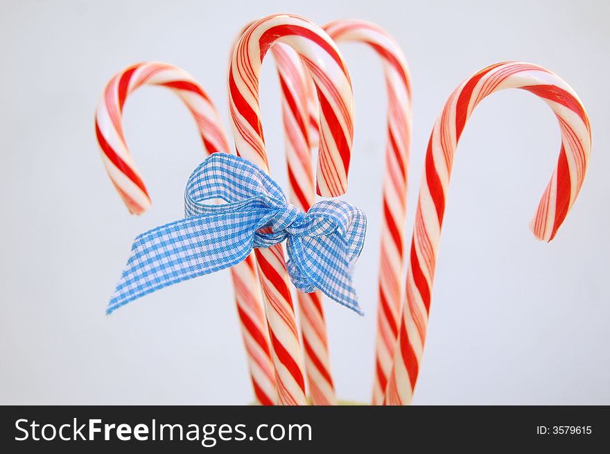 Candy canes tied with blue gingham bow, white background. Candy canes tied with blue gingham bow, white background