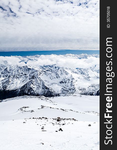 Mountain landscape in autumn or winter in Caucasus Mountains i Russia and Georgia. View from slopes of Mount Elbrus 5642m. Lot of white snow on rocky mountain ridge over blue sunny sky, Russia. Mountain landscape in autumn or winter in Caucasus Mountains i Russia and Georgia. View from slopes of Mount Elbrus 5642m. Lot of white snow on rocky mountain ridge over blue sunny sky, Russia.