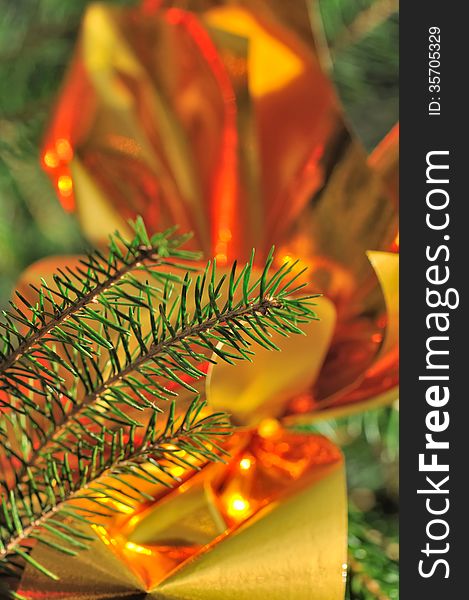 Branch of Christmas tree in front of golden decoration
