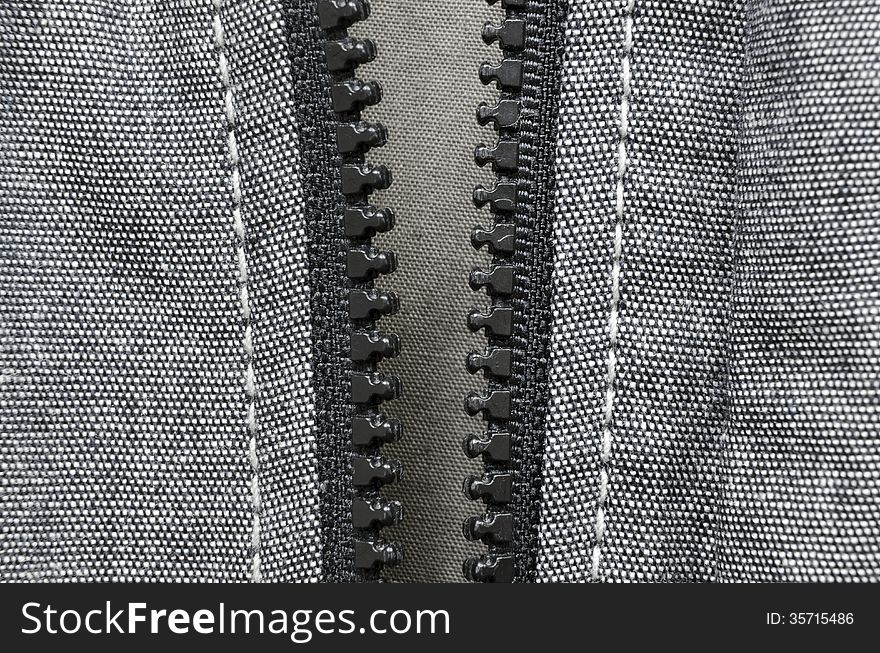 Fragment of open plastic zipper fastener of gray cotton jacket. Fragment of open plastic zipper fastener of gray cotton jacket