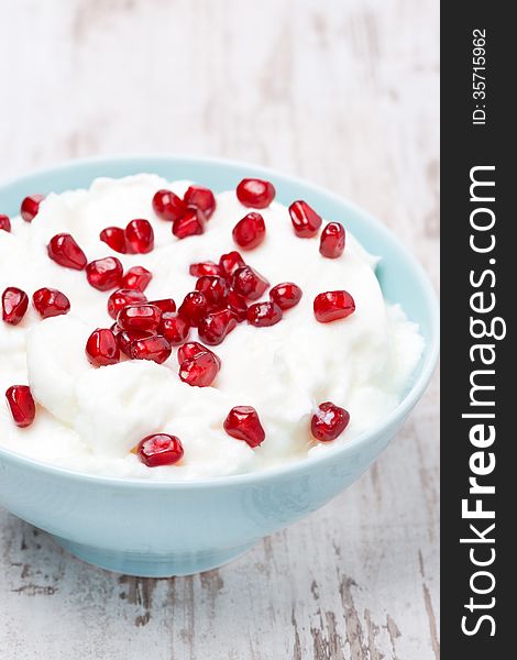 Homemade yogurt with pomegranate seeds in a bowl, vertical