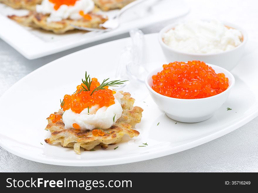 Potato pancakes with red caviar on the plate, horizontal