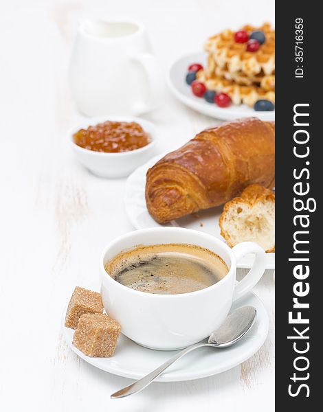 Sweet breakfast with black coffee, croissants, orange jam and waffles, vertical