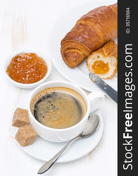 Fresh breakfast with black coffee, croissants and orange jam, top view, vertical