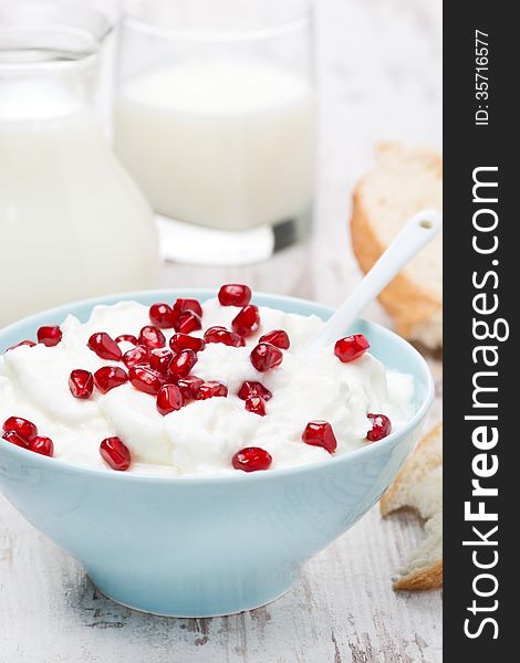 Fresh homemade yogurt with pomegranate, milk and bread for breakfast, vertical