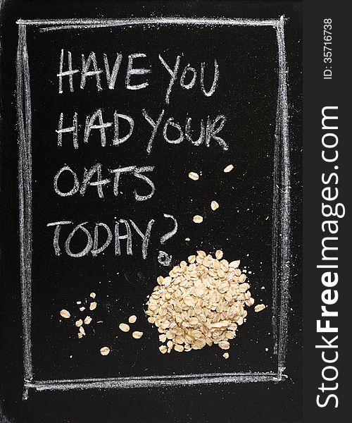 Have You Had Your Oats Today? Hand written on a used blackboard with a pile of porridge oats alongside as a concept for healthy eating.