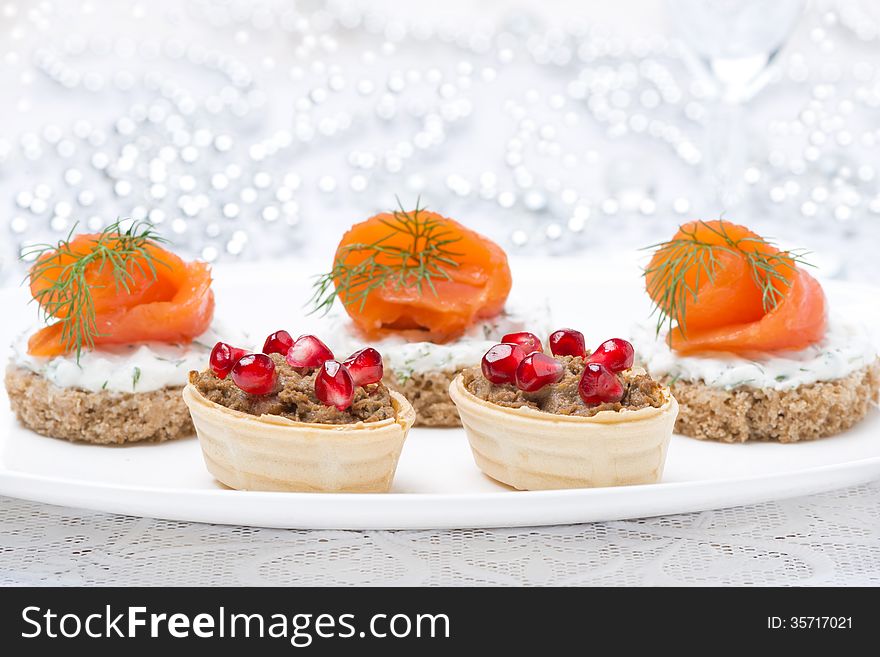 Holiday appetizers - canape with salmon and tartlet with liver pate for Christmas, selective focus, close-up. Holiday appetizers - canape with salmon and tartlet with liver pate for Christmas, selective focus, close-up
