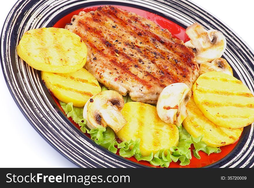 Roasted Turkey Steak Garnished with Grilled Sliced Potato, Portabello Mushrooms and Lettuce closeup on Striped Plate