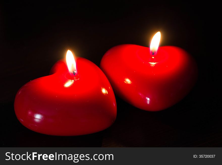 Two red candles in the form of heart close up