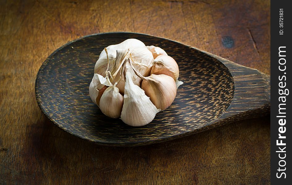 Garlic with peel on wood ladle in the kitchen. Garlic with peel on wood ladle in the kitchen